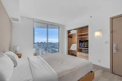 a white bedroom with a large bed and a window at Steps to the Sand Beachfront Escape- 25th Floor Views in Miami Beach