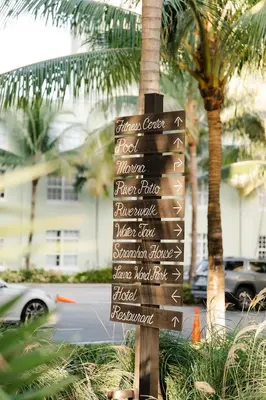 a directional sign in front of a palm tree at Riverside Hotel in Fort Lauderdale