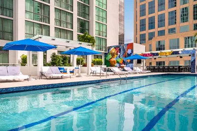 a swimming pool with chairs and umbrellas and buildings at Hyatt Centric Las Olas Fort Lauderdale in Fort Lauderdale