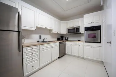 a kitchen with white cabinets and a stainless steel refrigerator at Paradise on Hollywood Beach 2 bed 2 bath in Hollywood