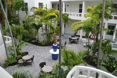 an outdoor patio with chairs and tables and trees at The Drift Hotel in Fort Lauderdale