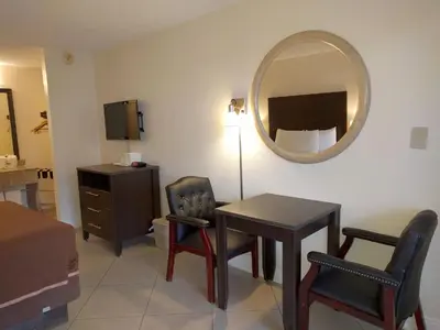 a room with a table and chairs and a mirror at Red Carpet Inn Airport Fort Lauderdale in Fort Lauderdale