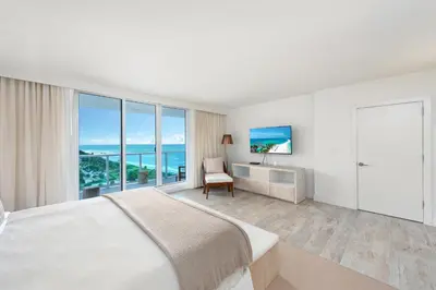 a bedroom with a bed and a desk and windows at Oceanfront Private Condo at 1 Hotel & Homes -1219 in Miami Beach