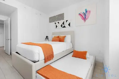 a white bedroom with an orange blanket on a bed at Wrap Around Balcony - Insane Views - Amazing Pools in Hollywood
