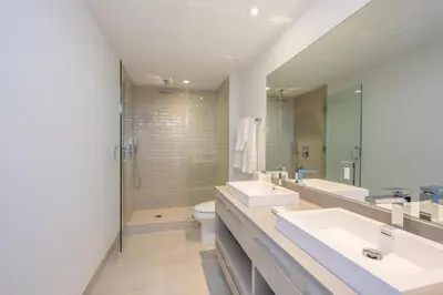 a bathroom with two sinks and a toilet and a mirror at Ocean Breeze Retreat - Pool Gym Access Views in Hallandale Beach