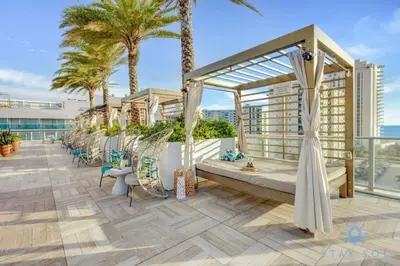 a balcony with chairs and palm trees on a building at Wrap Around Balcony - Paradise Beach - Amazing Pools in Hollywood