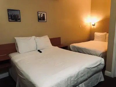 two beds in a hotel room with white sheets at Haven Hotel - Fort Lauderdale Airport & Cruise Port in Fort Lauderdale