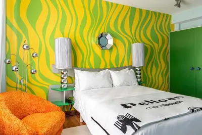 a bedroom with a bed and a yellow and green wall at Pelican Hotel in Miami Beach