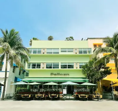 a hotel with tables and umbrellas in front of it at Pelican Hotel in Miami Beach