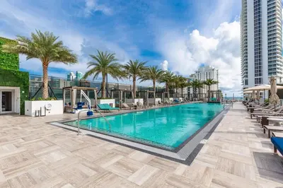 a swimming pool with palm trees and a building at Relaxing Getaway with Intracoastal Views in Hollywood