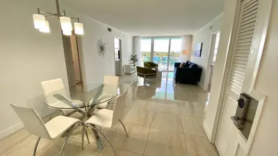 a dining room with a glass table and white chairs at Seacoast by Miami Ambassadors in Miami Beach