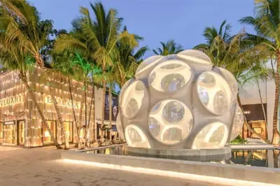 a large sculpture in front of a building with palm trees at Casa Madeira @ the heart of Miami Design District in Miami