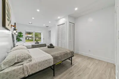 two beds in a bedroom with white walls and wood floors at Lakeside Vacation Home in Davie