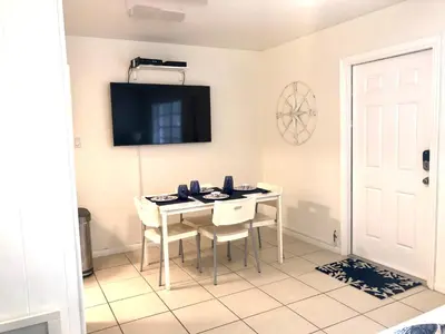 a dining room with a table and chairs and a tv at Gorgeous Beachy Chic Condo in Key Biscayne in Miami