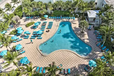 an aerial view of a resort pool with blue chairs and palm trees at Beachfront Condo with Pool Access in Hollywood! in Hollywood