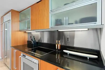 a kitchen with black counter tops and wooden cabinets at Oceanview Private Condo at The Setai -2401 in Miami Beach