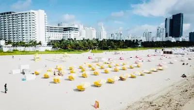 a group of yellow umbrellas on a beach with buildings at Casa Sofi in Miami Beach