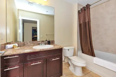 a bathroom with a sink and a toilet and a mirror at Dharma Home Suites South Miami at Red Road Commons in Miami