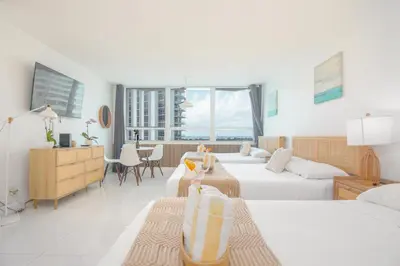 a bedroom with two beds and a desk and a table at Girasole Apartments in Miami Beach