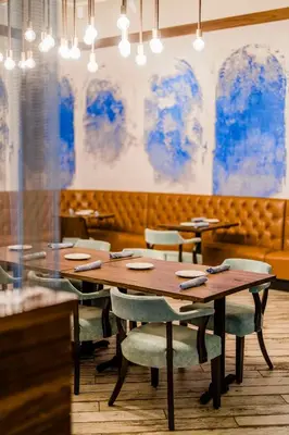 a dining room with tables and chairs and blue paintings at Hotel Maren Fort Lauderdale Beach, Curio Collection By Hilton in Fort Lauderdale