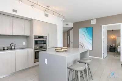 a kitchen with white cabinets and a kitchen island with stools at Corner Balcony - Enjoy 360 Views- Near Beach- Pool in Hollywood