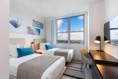two beds in a room with a desk and a television at Hyde Beach House Luxury Condo-Resort 2808 condo in Hollywood Beach