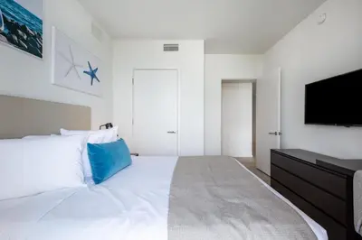 a white bedroom with a large bed and a flat screen tv at Family 3 bedroom Hyde Beach House Miami 22th floor in Hallandale Beach