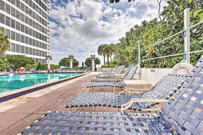 a row of lounge chairs next to a swimming pool at Waterfront High-Rise Condo - Miami Beach 5 Mi in Miami