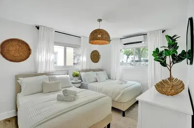 a white bedroom with two beds and a couch at Lincoln Villa Suites in Miami Beach