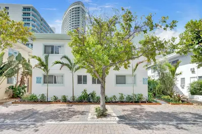 a tree in front of a white building with palm trees at Lincoln Villa Suites in Miami Beach