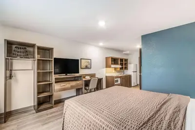a bedroom with a bed and a desk with a television at WoodSpring Suites Doral Miami Airport in Miami