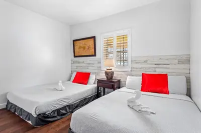two beds in a room with red and white pillows at South Beach Suites in Ocean Drive in Miami Beach