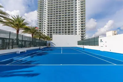 a tennis court in front of a tall building at Penthouse 2 Terraces Ocean Views Beach Access in Hollywood