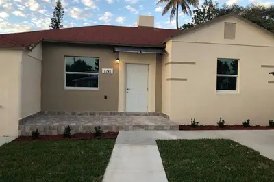 a house with a white door and a palm tree at Your House in Miami in Miami