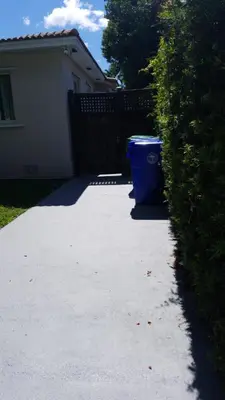 a blue trash can sitting on the side of a driveway at LUXURY Guayabita's House in Miami