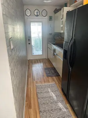 a kitchen with a refrigerator and a wooden floor at Ne Miami Cottage in Miami