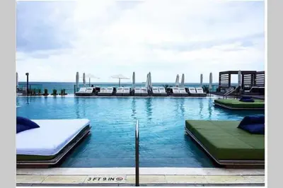 a swimming pool with beds and the ocean in the background at Incredible Ocean Views! Terrace, 1800 sq.ft., Hotel in Miami Beach