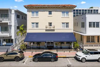 two cars parked in a parking lot in front of a building at Nine20 Collins Apartments by Lowkl in Miami Beach