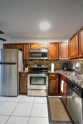 a kitchen with wooden cabinets and stainless steel appliances at Little Paris by the ocean self check in in Fort Lauderdale