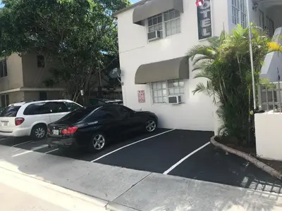 two cars parked in a parking lot in front of a building at Little Paris by the ocean self check in in Fort Lauderdale