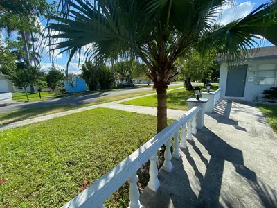 a white fence and a palm tree on a street at Sophisticated Dania Beach Suites Near the Beach in Dania Beach