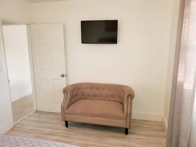 a brown chair in a room with a tv on a wall at Sophisticated Dania Beach Suites Near the Beach in Dania Beach