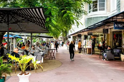 a group of people walking down a street with tables and chairs at Rock Apartments by Lowkl in Miami Beach