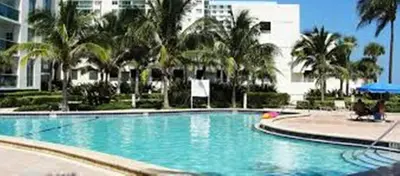 a large swimming pool with palm trees and a building at Apartamento en la Playa The Tides in Hollywood