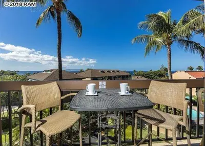 a table and chairs on a balcony with palm trees at South Maui Condos in Miami Beach