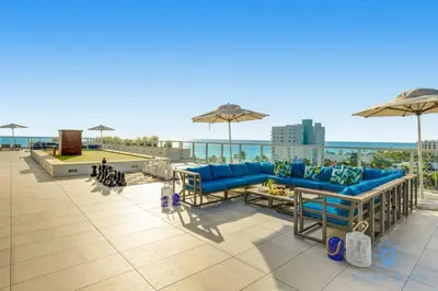 a patio with blue couches and umbrellas on a roof at Near Beach - Rooftop Pool - Hot Tub - Broad-walk in Hollywood
