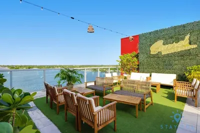 a patio with wooden tables and chairs and the water at Near Beach - Rooftop Pool - Hot Tub - Broad-walk in Hollywood