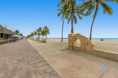 a sidewalk next to a beach with palm trees at Amazing Pool - Hot Tub - Gym - Hollywood Beach in Hollywood