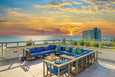 a living room with a couch on a balcony overlooking the ocean at Best Stay - Rooftop Pool - Broad - walk - Near Beach in Hollywood