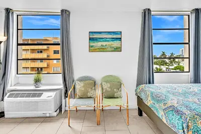 a bedroom with a bed and two chairs and windows at Lovely apartment in the heart of South Beach in Miami Beach